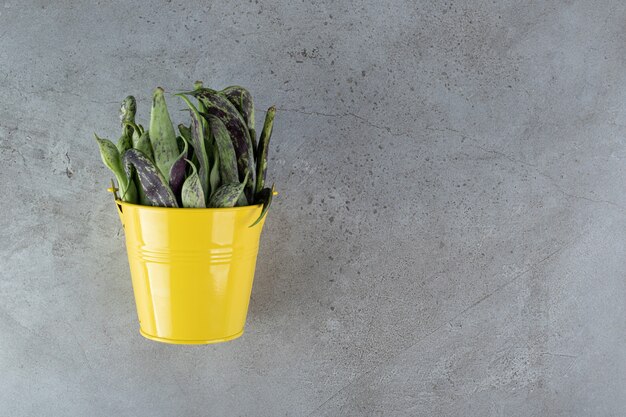 Un cubo amarillo con guisantes crudos sobre un fondo gris. Foto de alta calidad