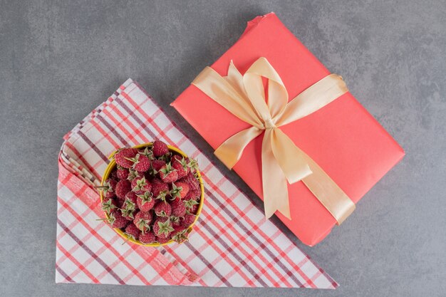 Cubo de fresas frescas y caja de regalo sobre superficie de mármol. Fotok de alta calidad