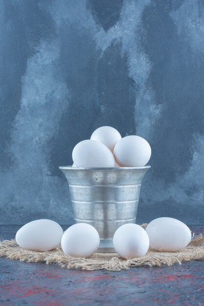 Un cubo metálico con huevos de gallina frescos crudos.