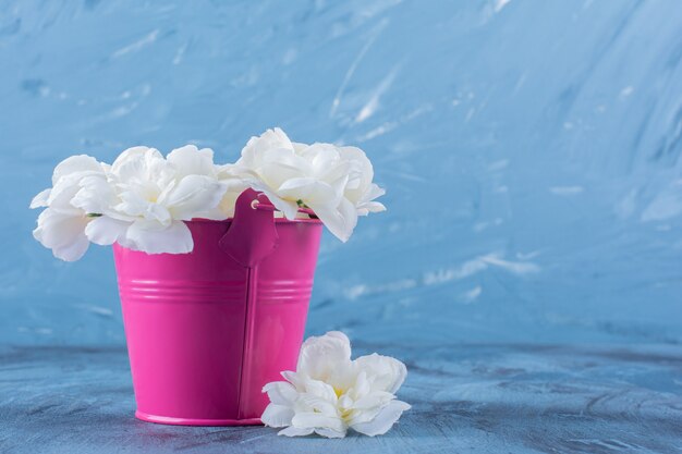 Un cubo rosa con un hermoso ramo de flores blancas.