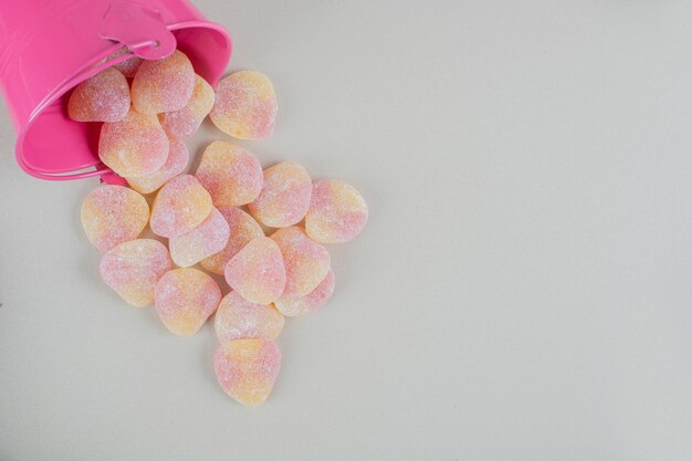 Un cubo rosa lleno de caramelos de gelatina en forma de corazón.