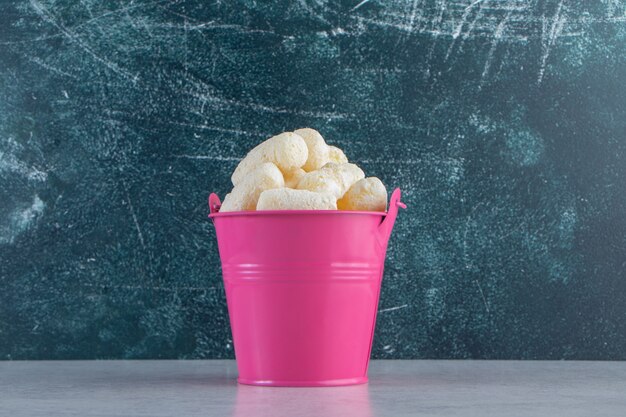 Cubo rosa de palitos de maíz dulce sobre fondo de piedra.