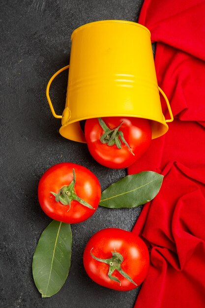 Cubo de vista superior con tomates rojos toalla roja sobre fondo oscuro