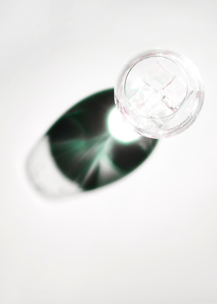 Cubos de hielo en copa transparente con sombra oscura brillante sobre fondo blanco