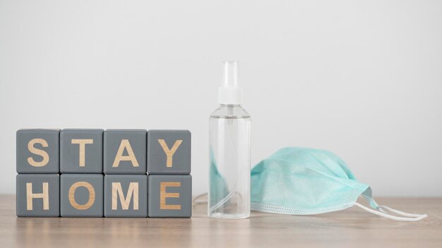 Cubos de madera con stay home y desinfectante de manos junto a la mascarilla médica