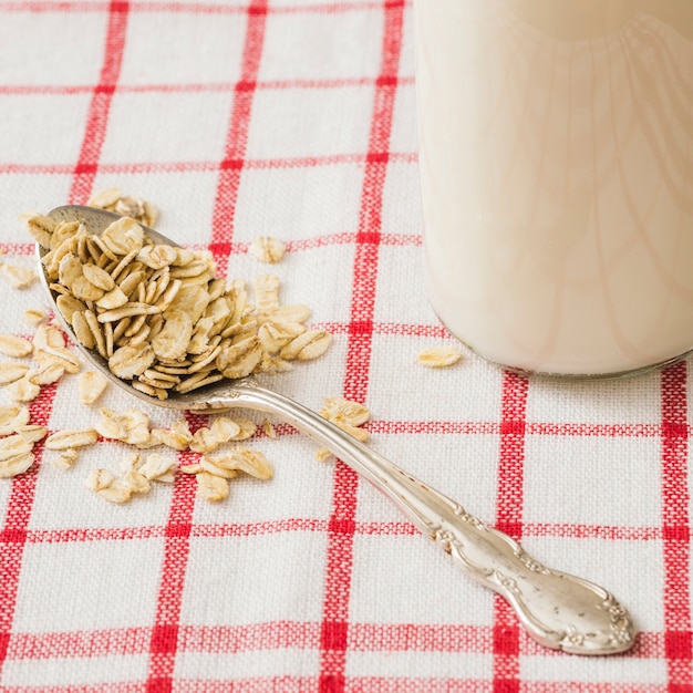 Foto gratuita cuchara de copos de avena en una cuchara vintage con leche en mantel