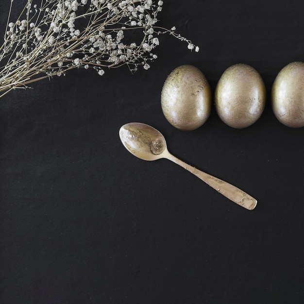 Cuchara y flores cerca de huevos de Pascua