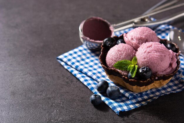 Cuchara de helado de arándanos sobre fondo de pizarra negra