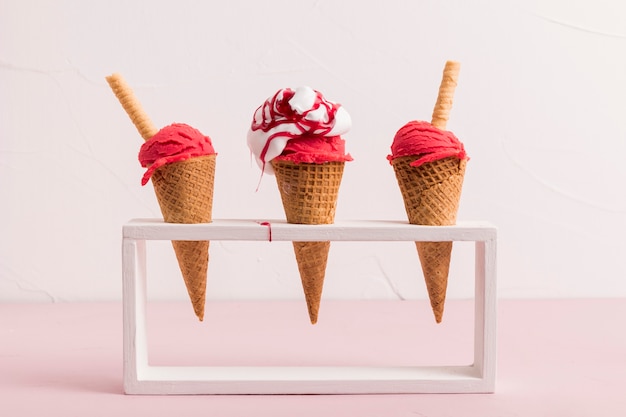 Cuchara de helado rojo en conos con almíbar y paja de waffle en el stand