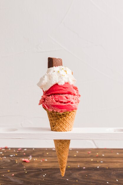 Cuchara de hielo rojo congelado con crema batida y chocolate en cono