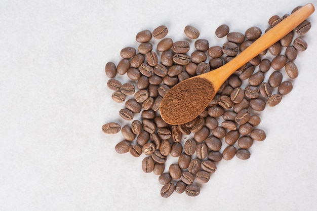 Una cuchara de madera de cacao en polvo con granos de café. Foto de alta calidad