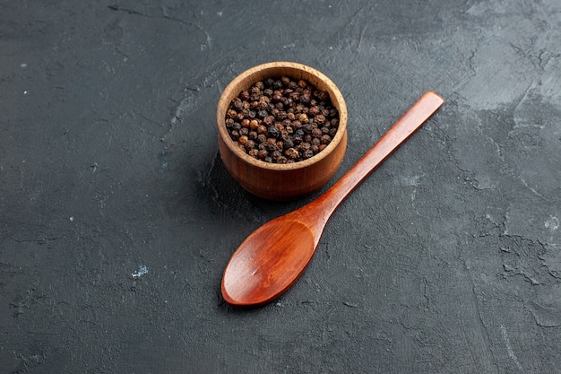 Foto gratuita cuchara de madera del cuenco de la pimienta negra de la vista inferior en lugar oscuro copia de la superficie