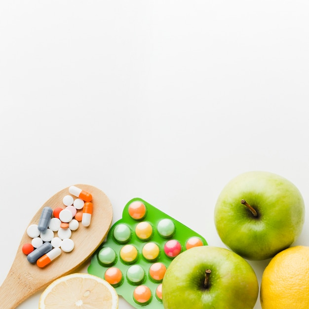 Cuchara de madera llena de pastillas y manzanas.