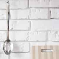 Foto gratuita cuchara de metal colgada en pared de ladrillo blanco