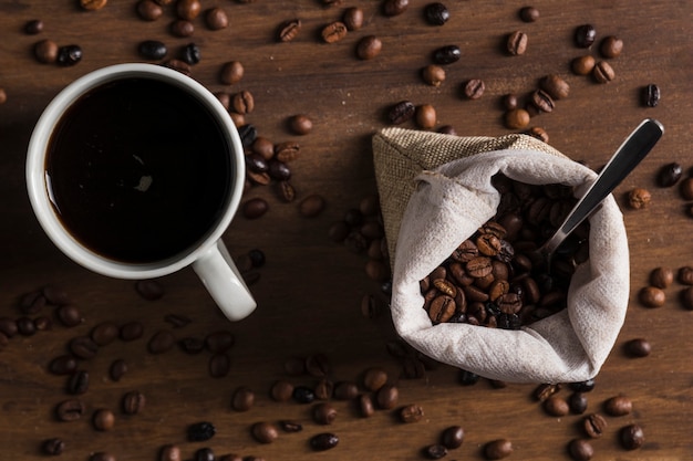 Foto gratuita cuchara en saco con granos de café y taza de bebida.