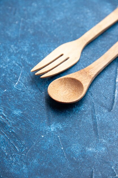 Cuchara tenedor de madera vista inferior sobre superficie azul