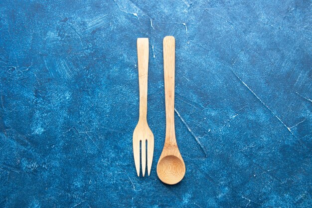 Cuchara de tenedor de madera vista superior en mesa azul con espacio libre