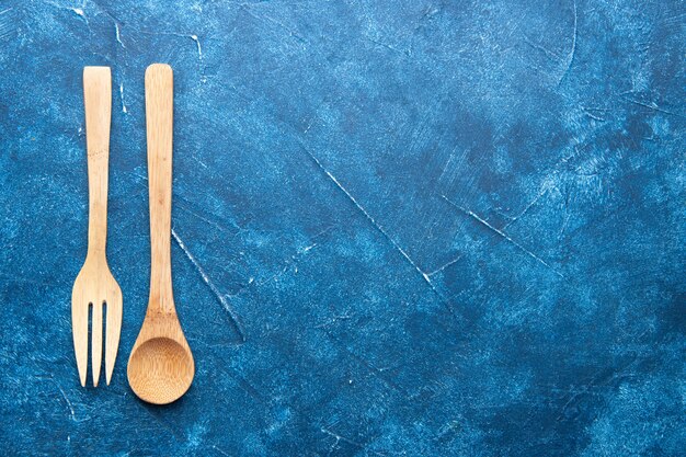 Cuchara tenedor de madera vista superior en mesa azul con lugar de copia