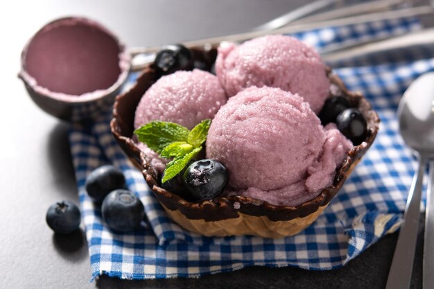 Cucharadas de helado de arándanos con gofre sobre fondo negro