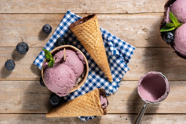 Cucharadas de helado de arándanos con waffle sobre mesa de madera