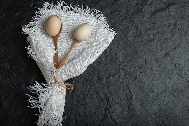 Cucharas de madera de huevos de gallina sobre arpillera