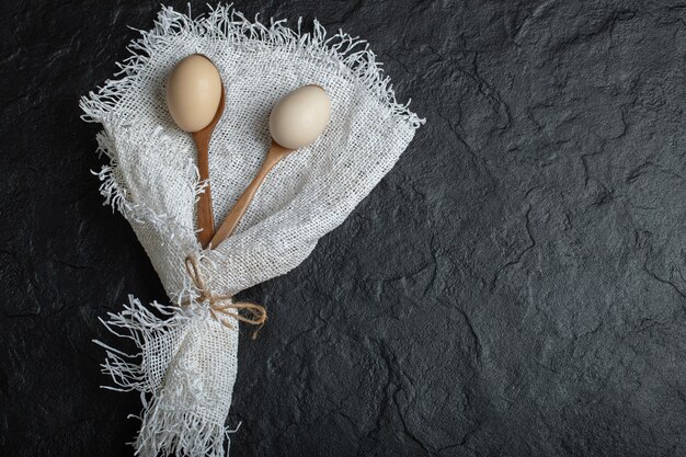 Cucharas de madera de huevos de gallina sobre arpillera