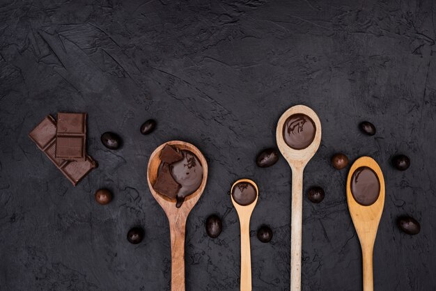 Cucharas de madera con jarabe de chocolate y barras de chocolate.