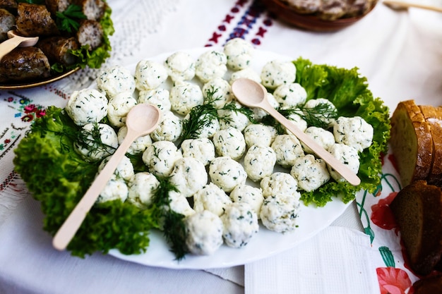 Las cucharas de madera mienten en plato con bolas de queso y vegetación