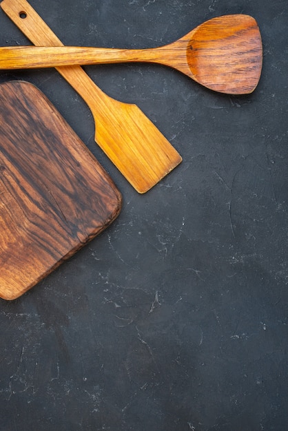 Cucharas de madera del tablero de madera de la vista superior en el lugar oscuro de la copia de la mesa