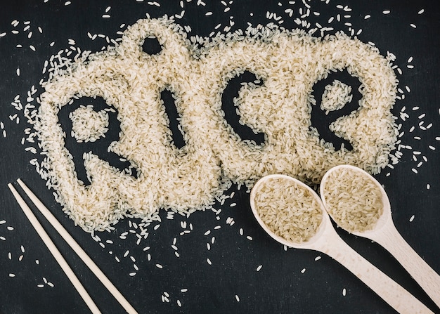 Cucharas y palillos cerca de la escritura de arroz