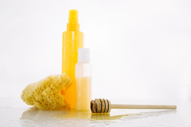 Cucharón de miel cerca de productos de cuidado de la piel y esponja