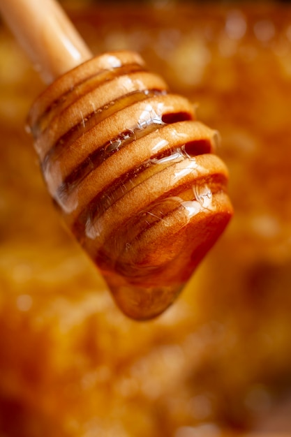 Foto gratuita cucharón de miel de madera con goteo de miel