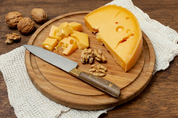 Foto gratuita cuchillo de alto ángulo y queso en un tablero