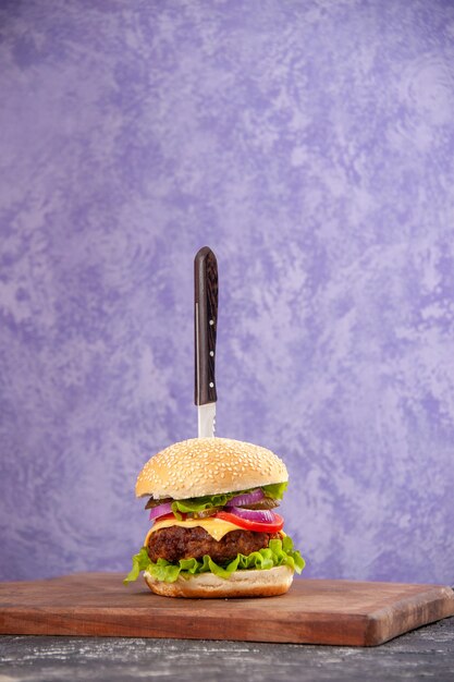 Cuchillo en un delicioso sándwich de carne sobre una tabla de cortar de madera sobre una superficie de hielo aislada con espacio libre