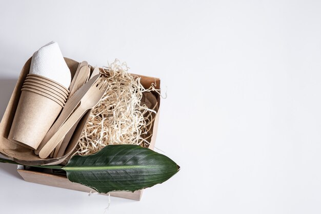 Cuchillos, tenedores, vasos, envases de papel para comida y una hoja natural. El concepto de desperdicio cero y libre de plástico.