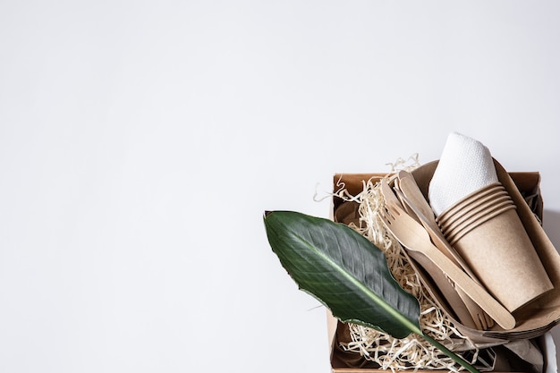 Cuchillos, tenedores, vasos, envases de papel para comida y una hoja natural. El concepto de desperdicio cero y libre de plástico.