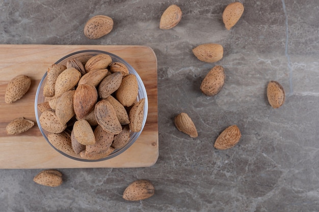 Foto gratuita un cuenco de almendras en una bandeja y almendras esparcidas sobre la superficie de mármol