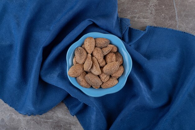 Un cuenco de almendras sobre la toalla sobre la superficie de mármol.