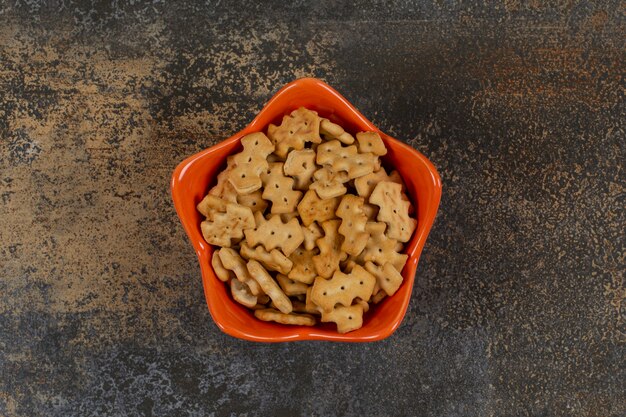 Cuenco anaranjado de galletas en mármol.