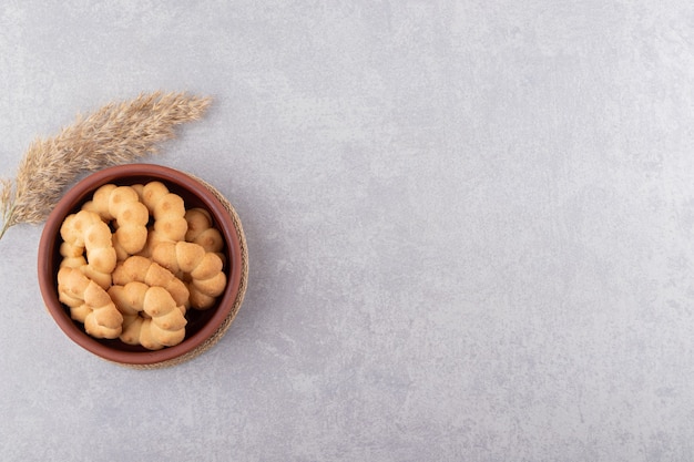 Cuenco de arcilla de galletas dulces en forma de flor en la mesa de piedra.