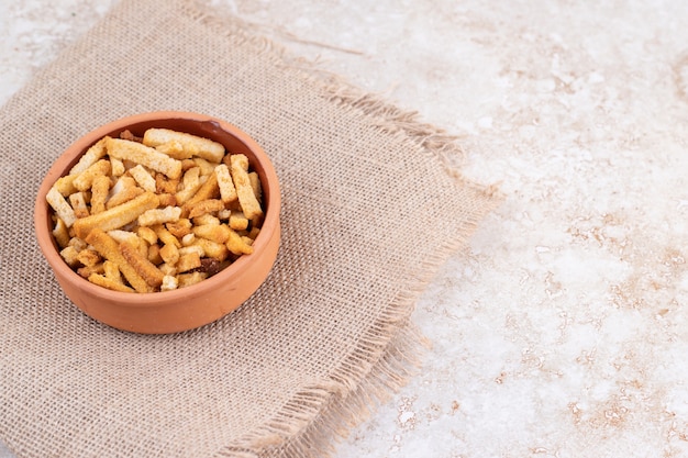 Un cuenco de arcilla con palitos de pan sobre una tela de saco