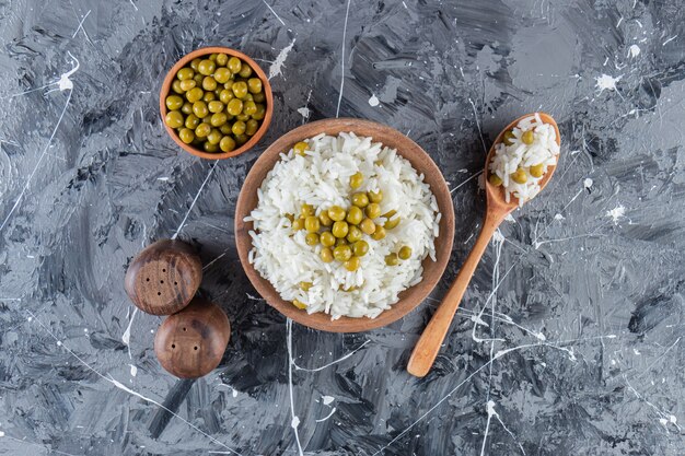 Cuenco de arroz blanco al vapor con guisantes sobre fondo de mármol.