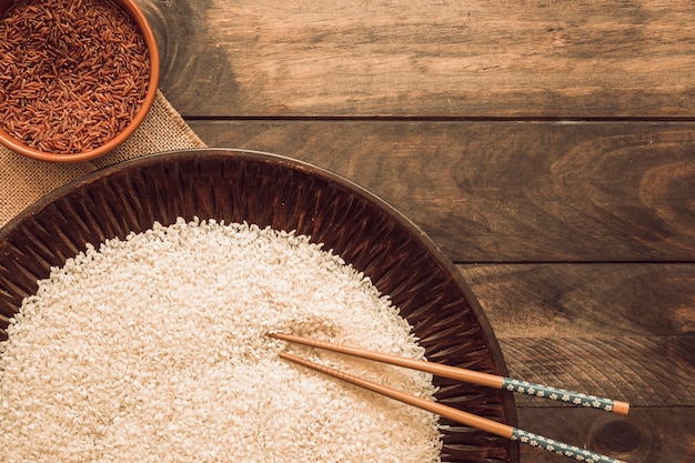 Cuenco de arroz rojo jazmín y grano de arroz blanco en bandeja con palillos