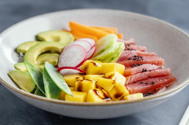 Cuenco de atún crudo saludable con verduras servidas en el plato Primer plano