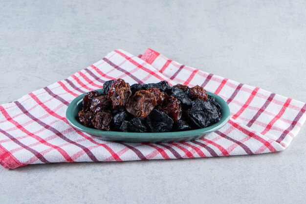 Cuenco azul de deliciosos dátiles secos sobre fondo de piedra.