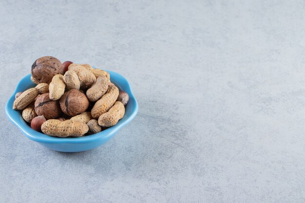 Cuenco azul de frutos secos orgánicos colocados sobre fondo de piedra.