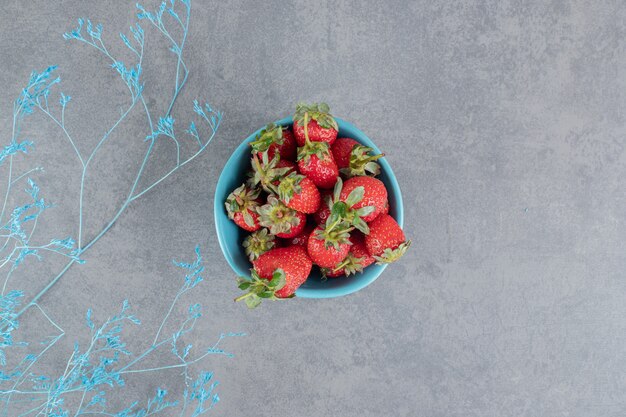 Un cuenco azul lleno de deliciosas fresas. Foto de alta calidad