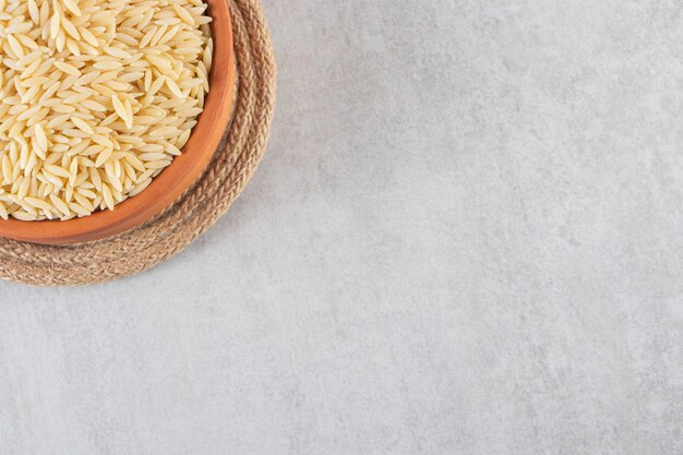 Cuenco de barro lleno de arroz crudo colocado sobre la mesa de piedra.