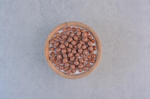 Cuenco de bolas de cereal de chocolate con leche en piedra.