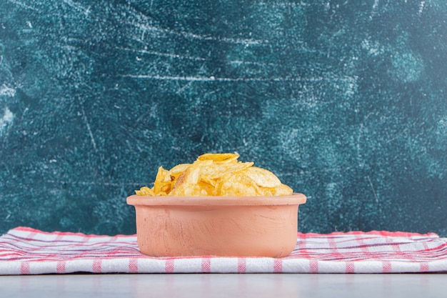 Cuenco de cerámica de deliciosas patatas fritas crujientes sobre fondo de piedra.